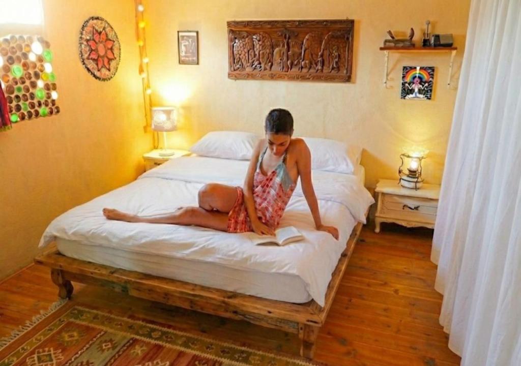 een vrouw zit op een bed bij Chen in Ezuz - Adults Only in ‘Ezuz