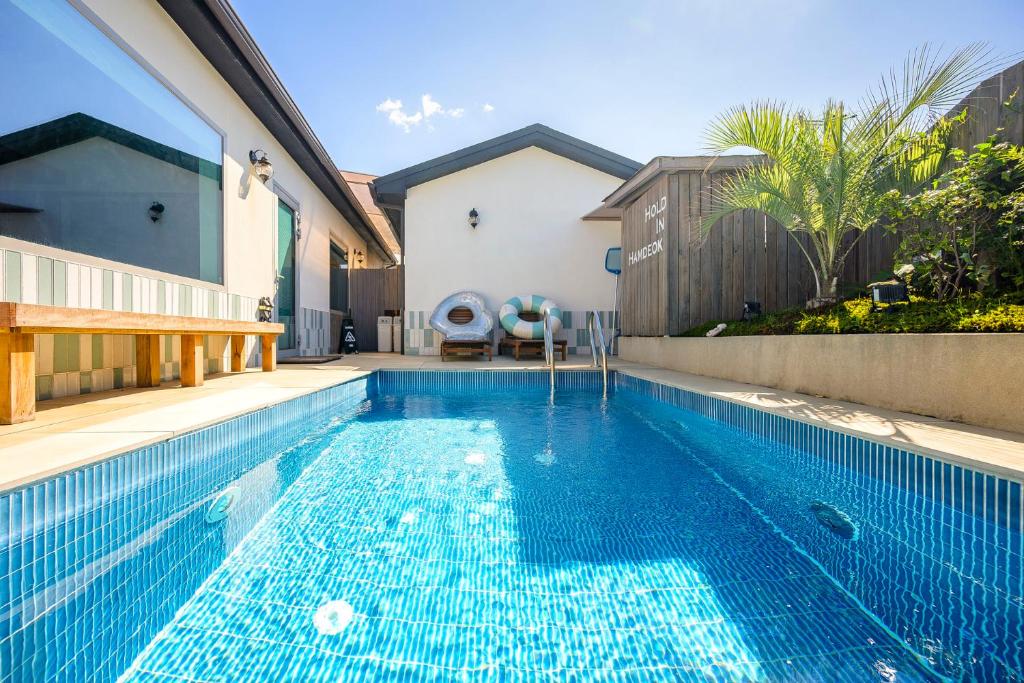 a swimming pool in a yard with a house at Hold in Hamdeok with Pool in Jeju