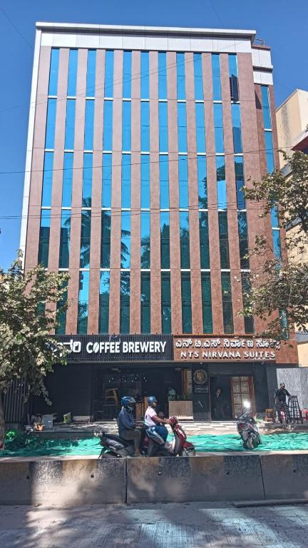 a building with two people on motorcycles in front of it at NTS Nirvana Suites in Bangalore