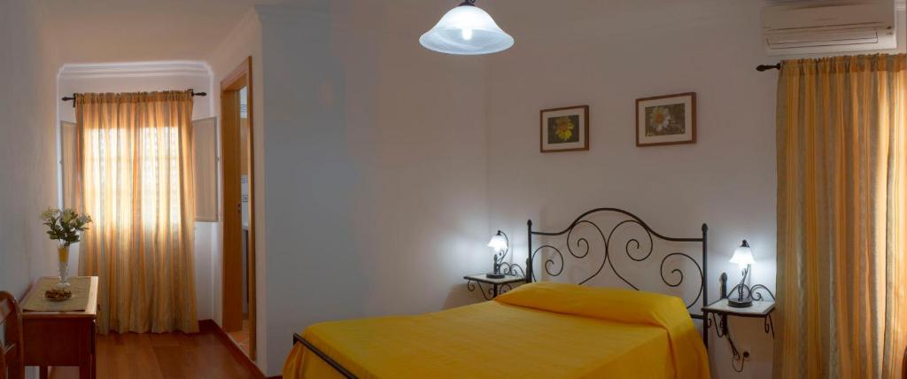 um quarto com uma cama com um cobertor amarelo em Quinta da Fonte do Lugar em Vera Cruz de Marmelar