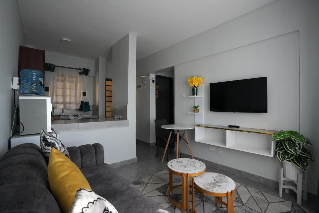 a living room with a couch and a tv at Modern 1-Bedroom Apartment Near Kisumu CBD, Free WiFi, Parking & Security in Kisumu