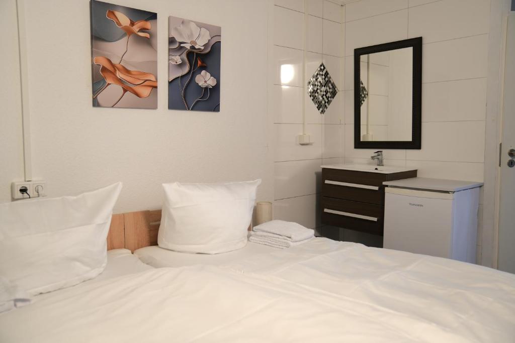 a bedroom with a white bed and a sink at Hotel am Schürblick in Gronau