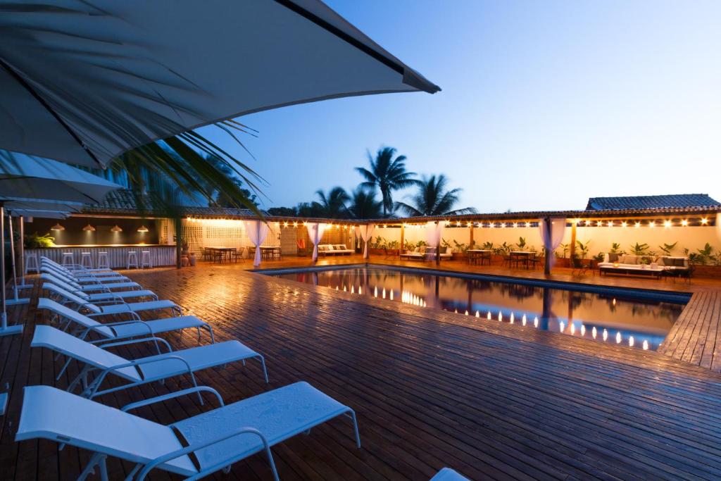 a pool with chairs and an umbrella in a building at Pousada Brisas do Espelho in Praia do Espelho