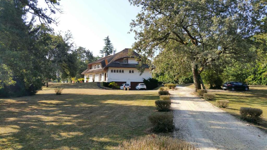 una casa grande con un coche aparcado delante de ella en La Belle Chaumière en Bretagne-de-Marsan