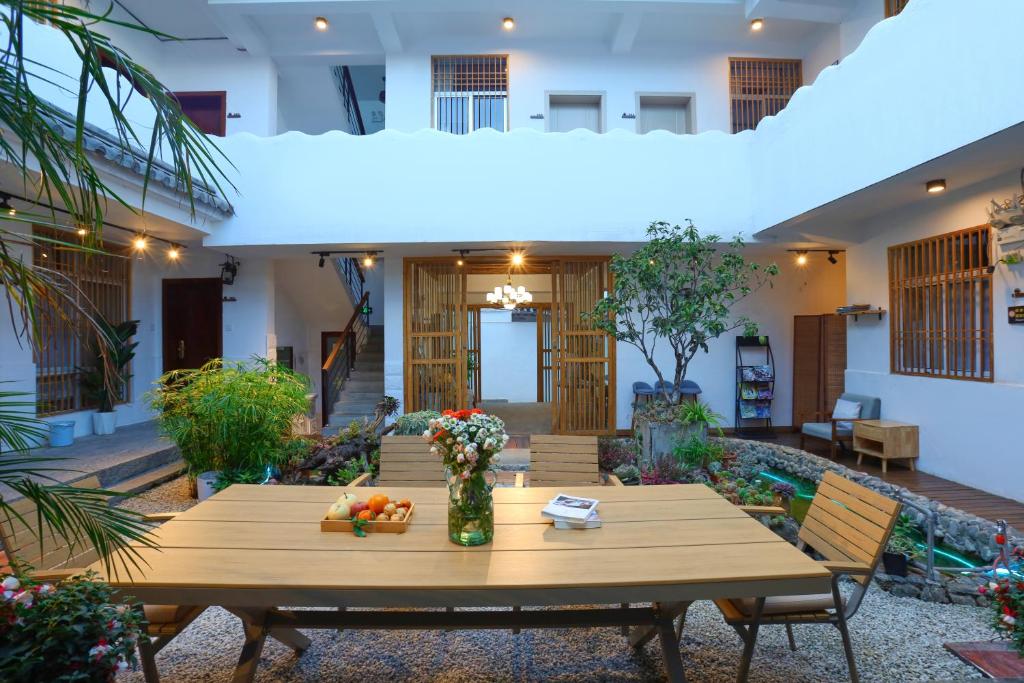 a table in the courtyard of a house with flowers at 大理六悦客栈Dali Liuyue Inn in Dali