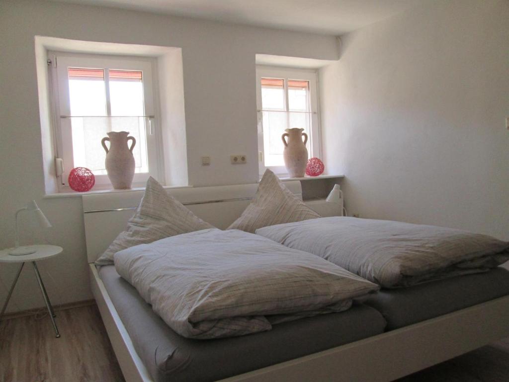 a bed in a room with two windows and vases at Ferienwohnungen Schneider-Kettern in Neumagen-Dhron