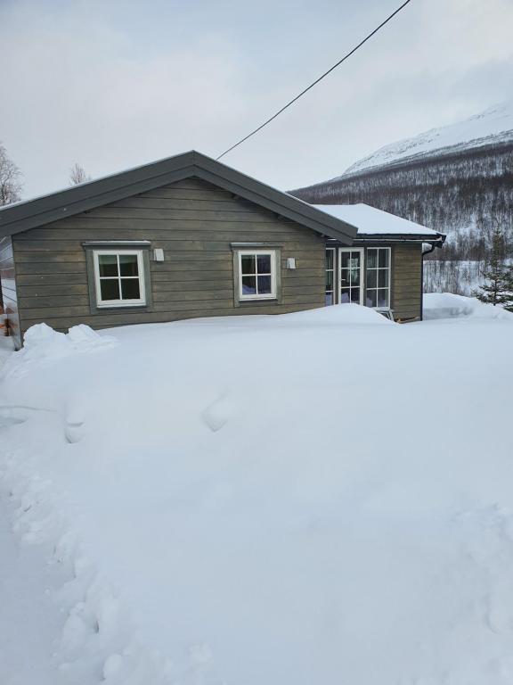 ein Haus mit einem Schneehaufen davor in der Unterkunft Wake up to the silence and beauty of the Lyngen Alps in Indre Tomasjord