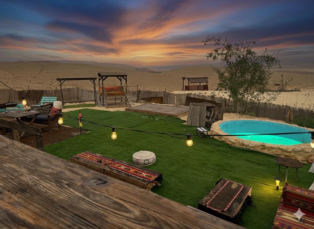 a backyard with a pool and a table and a ping at בית אירוח מרום במדבר in Dimona