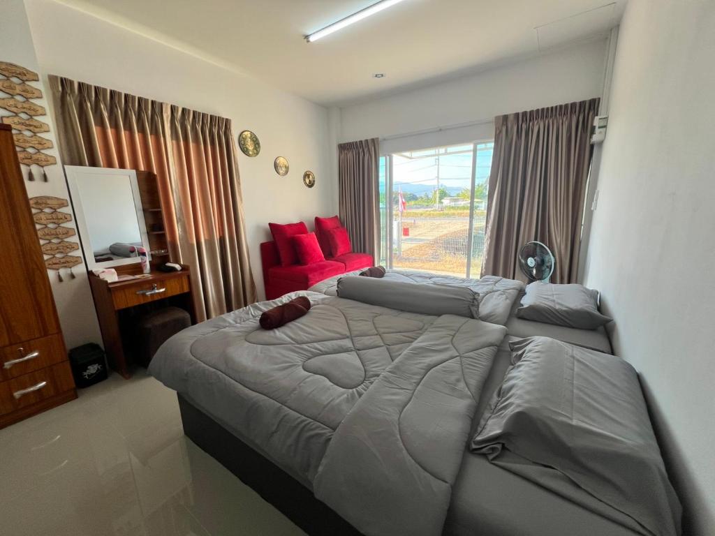 une chambre avec un grand lit et une chaise rouge dans l'établissement บ้านพักคุณอร, à Ban Ku Sua