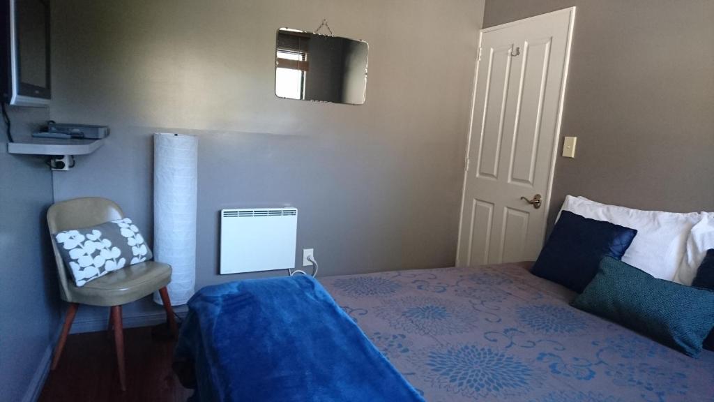 a bedroom with a blue bed and a chair at Waitapu Springs B&B in Takaka