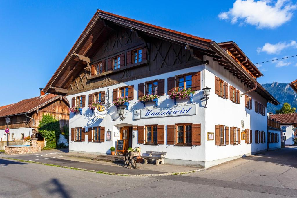 Un grand bâtiment blanc avec des fenêtres à volets en bois est disponible. dans l'établissement Landgasthof Hanselewirt, à Schwangau