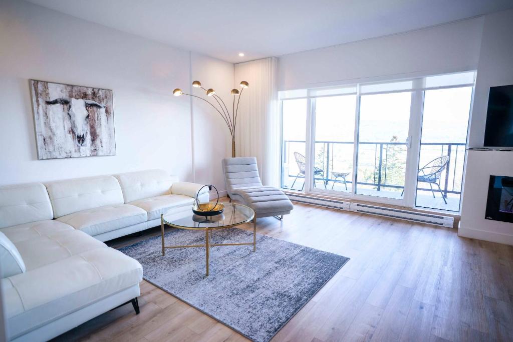 een woonkamer met een witte bank en een tafel bij 304 - Chic Minimalist Condo - River & Serenity in Baie-Saint-Paul