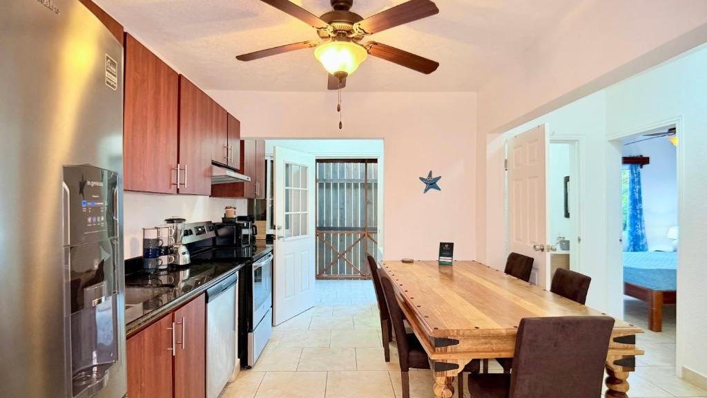 een keuken met een houten tafel en een plafondventilator bij Sunny dream in Sandy Bay