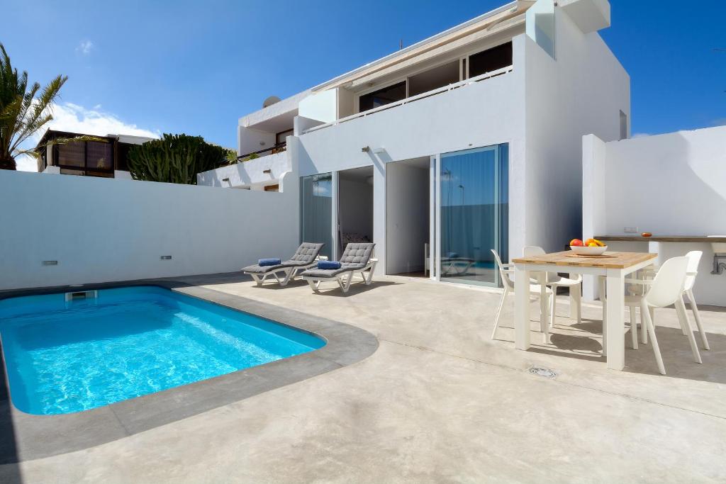 a villa with a swimming pool and a table and chairs at Villa Sunrise Private Pool Puerto del Carmen By PVL in Puerto del Carmen