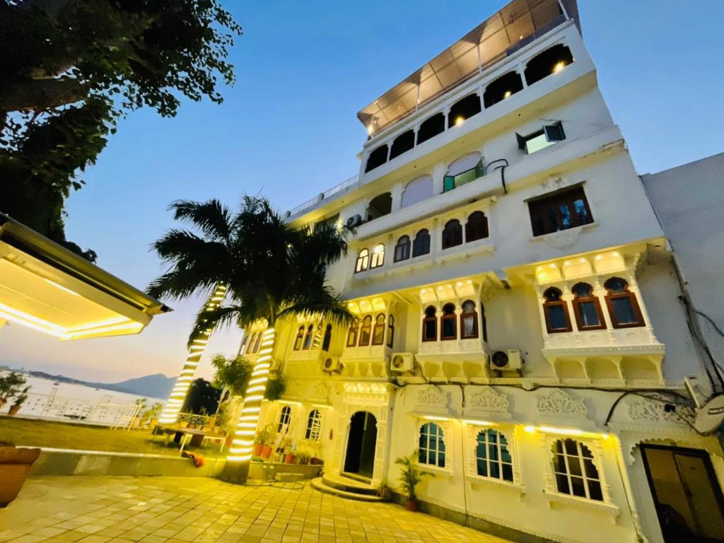 a white building with a palm tree in front of it at The Lake Haveli in Udaipur