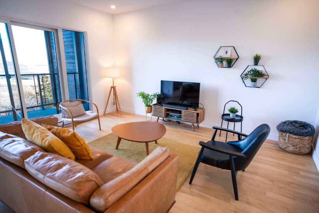 een woonkamer met een bank en een tv bij 309 - Luxury Condo - Spectacular View & Pool in Baie-Saint-Paul