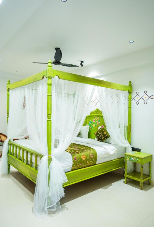 a bedroom with a green canopy bed with white drapes at Hotel Indiana Hitech City in Hyderabad