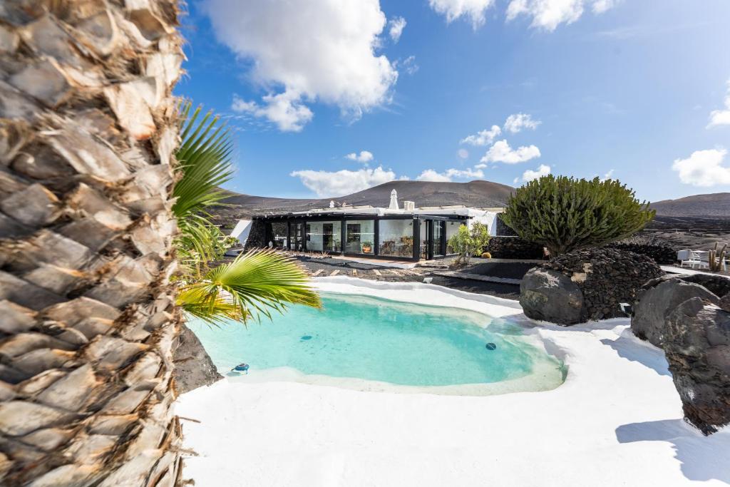 a swimming pool in the snow next to a house at La Geria Suites in Yaiza