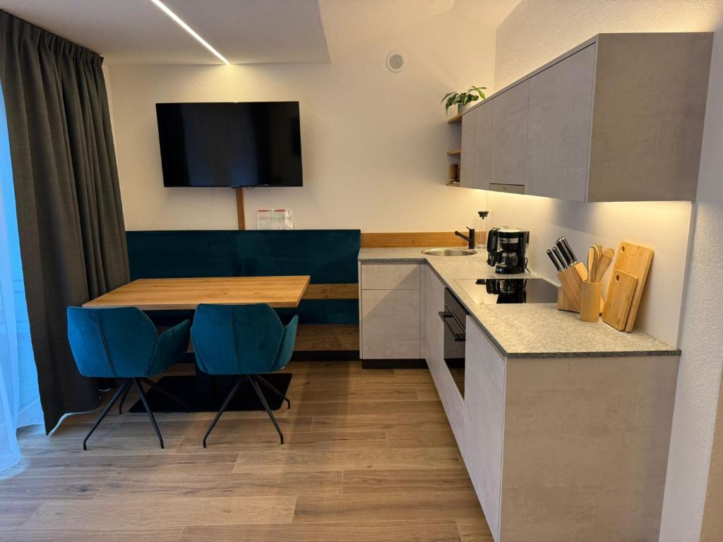 een keuken met een houten tafel en blauwe stoelen bij AurAlpin Apartments in Cadipietra
