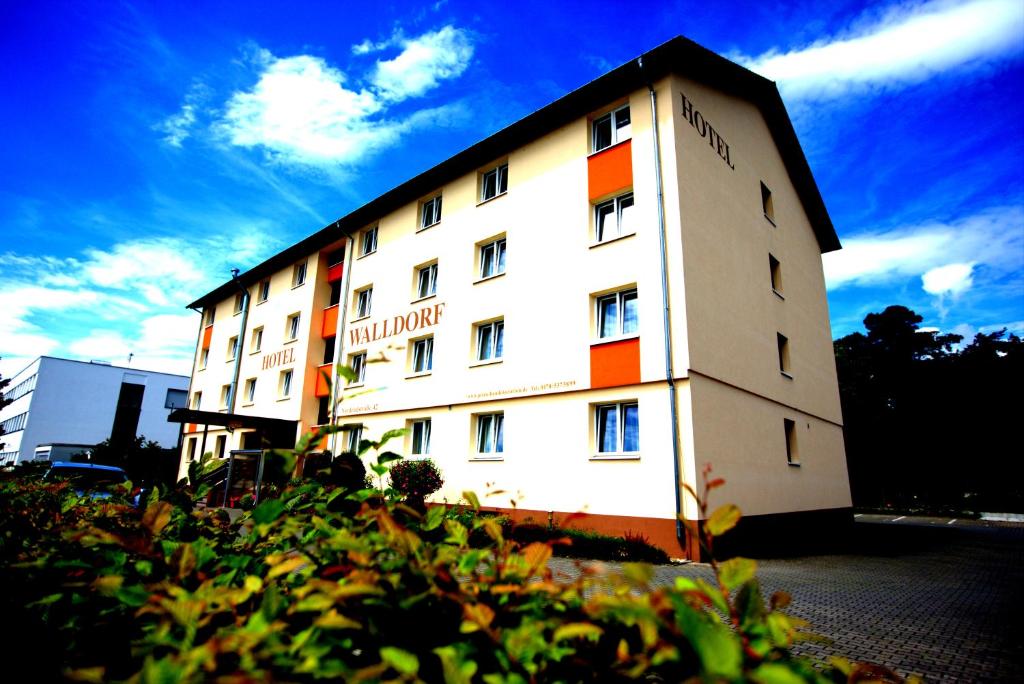 un edificio blanco con rayas naranjas a su lado en Airport Hotel Walldorf en Mörfelden-Walldorf