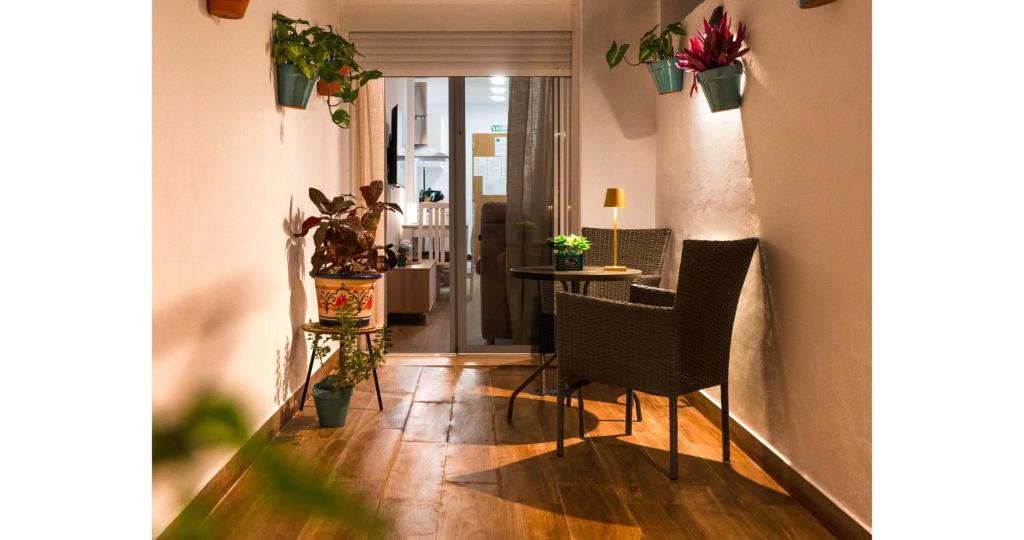 a hallway with a table and chairs and potted plants at YourHouse Apartamentos Andasol BB in Chipiona