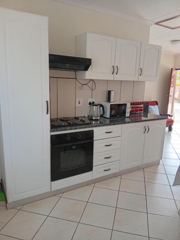 a kitchen with white cabinets and a stove top oven at VSA SELF CATERING unit 1 in Newcastle