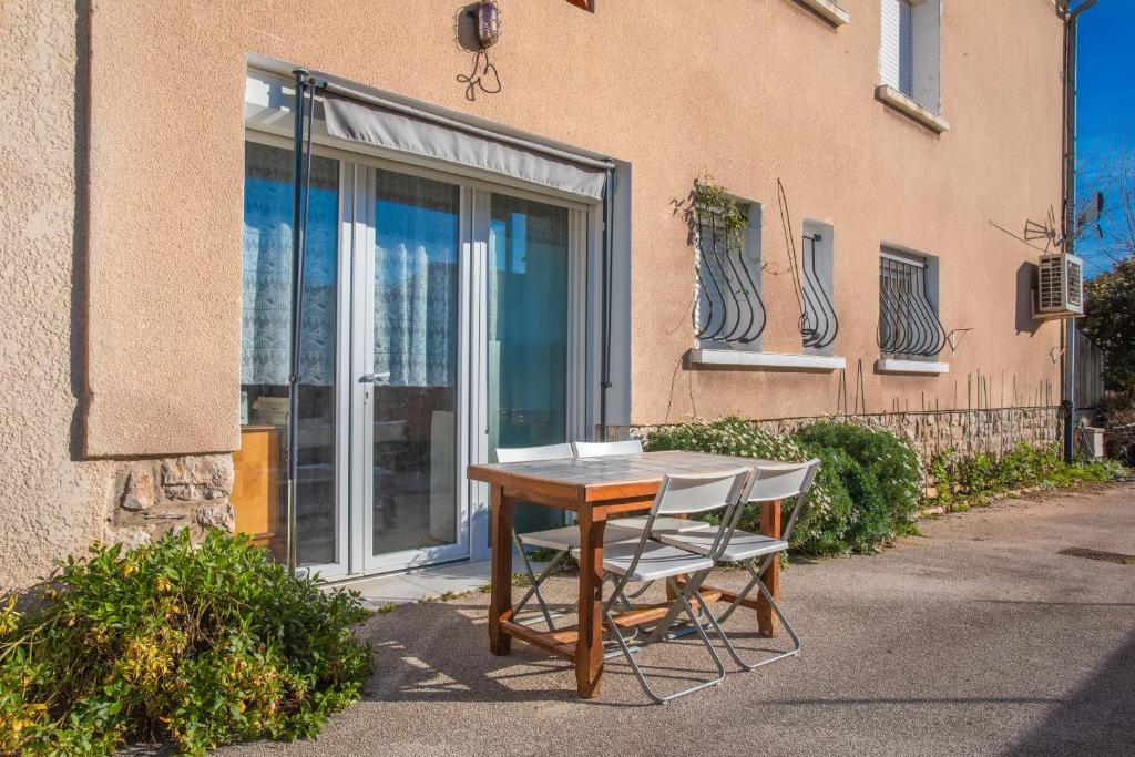 une table et deux chaises devant un bâtiment dans l'établissement Studio proche plage clim et parking, à Carqueiranne