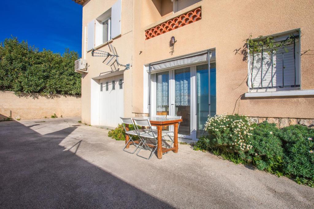 een tafel en een stoel voor een gebouw bij Studio Clim proche plage et parking in Carqueiranne