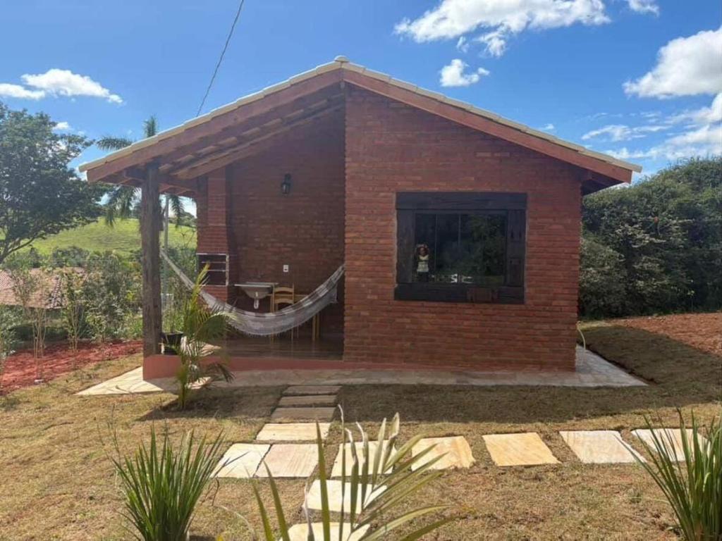 a small brick house with a hammock in the window at Recanto Boa Vista - Chalé 1 in São Thomé das Letras