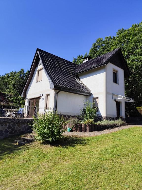 een wit huis met een zwart dak en een tuin bij Ferienhaus am See in Godendorf