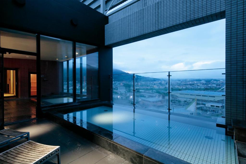 an indoor swimming pool in a building with a view at Candeo Hotels Chino in Chino