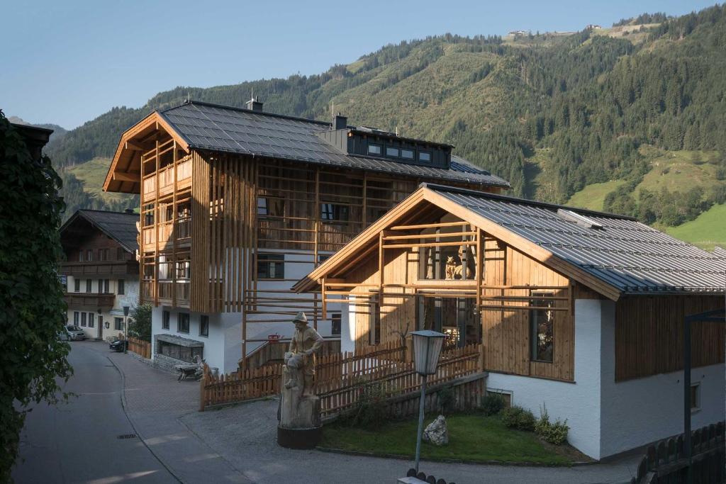 ein großes Holzhaus mit Bergen im Hintergrund in der Unterkunft Atelier Garni Astei in Großarl