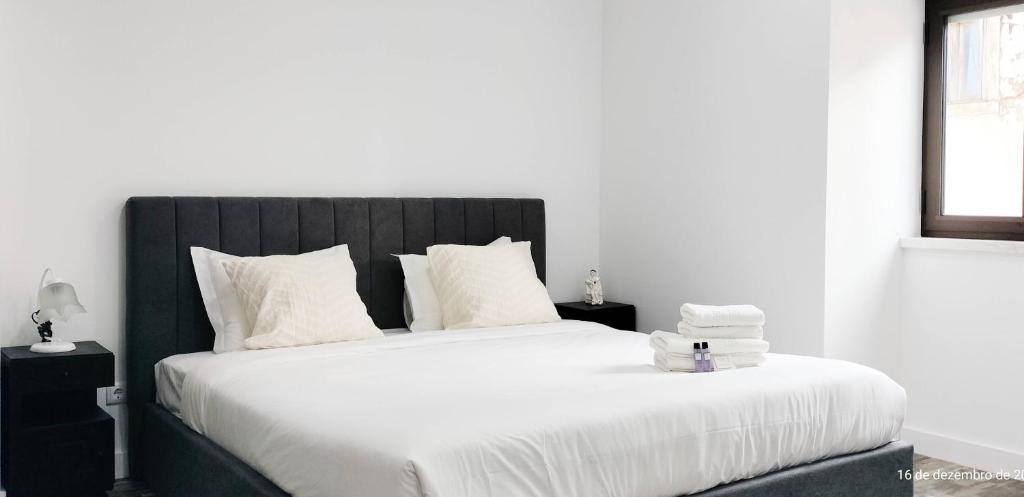une chambre avec un grand lit avec des draps et des oreillers blancs dans l'établissement Casa da Aldeia - Monte Redondo, à Figueira de Lorvão