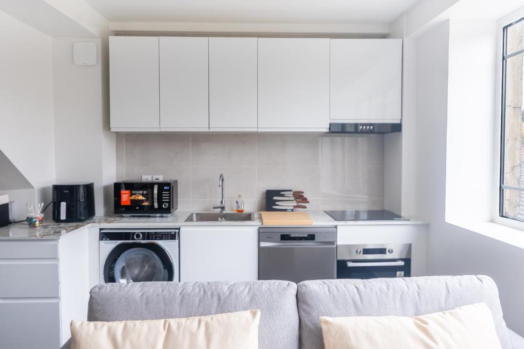 eine Küche mit weißen Schränken und einer Waschmaschine und einem Trockner in der Unterkunft Le Van G-Home in Auvers-sur-Oise