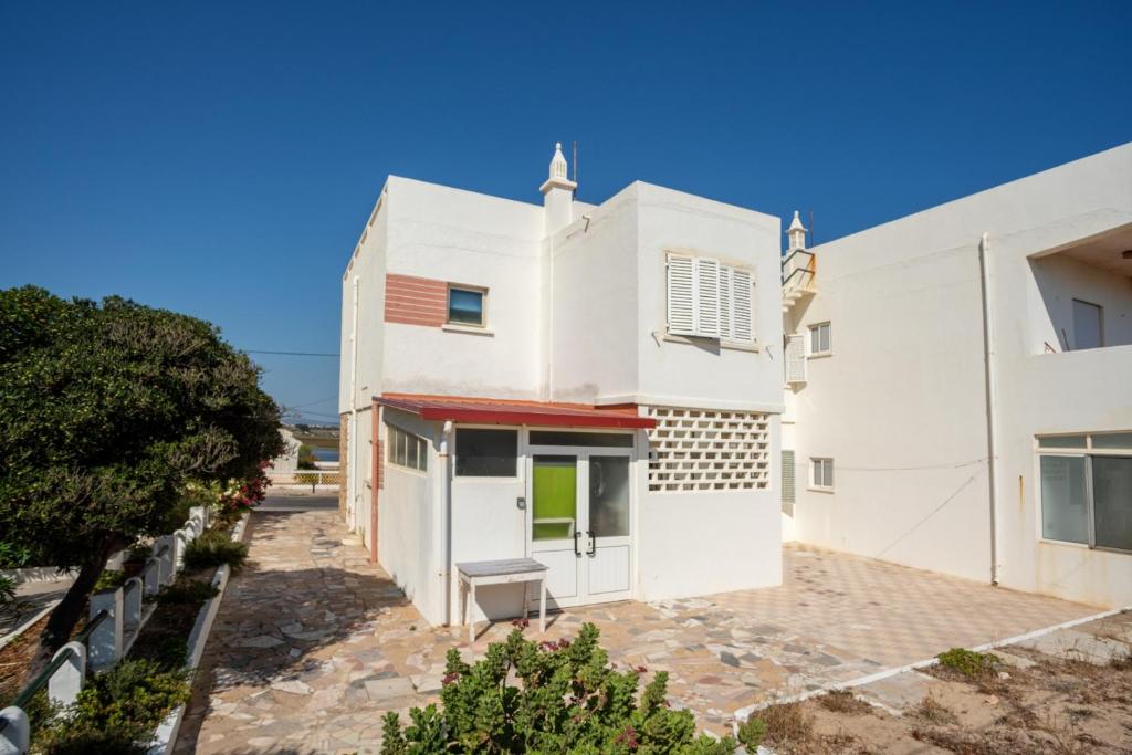 a white house with a bench in front of it at Blife Sonya private rooms at Faro beach in Faro