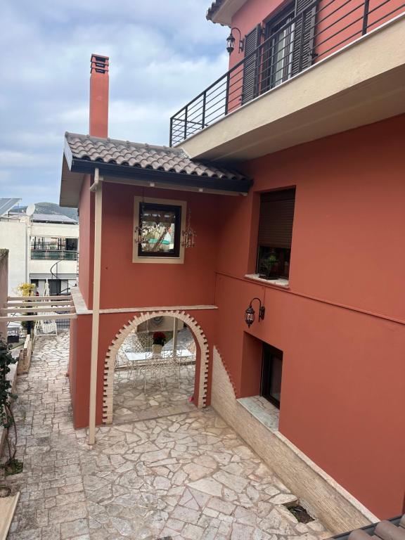 a red house with an archway on the side of it at Garden house in Arta