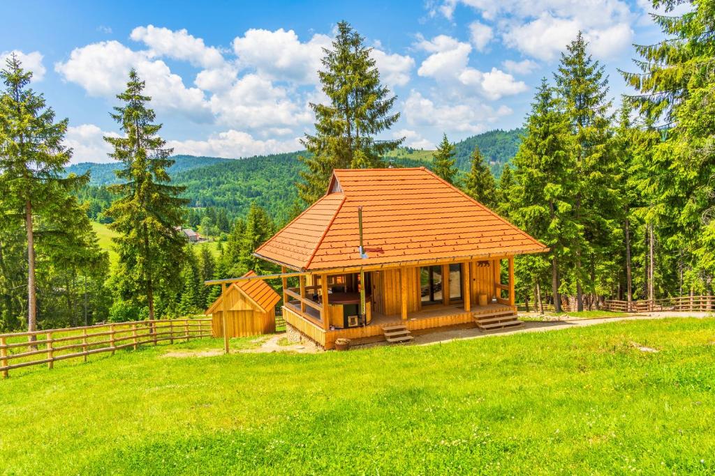 a log cabin in a field with a fence at MyNest - Mountain luxury cabin in Plăeşii de Sus