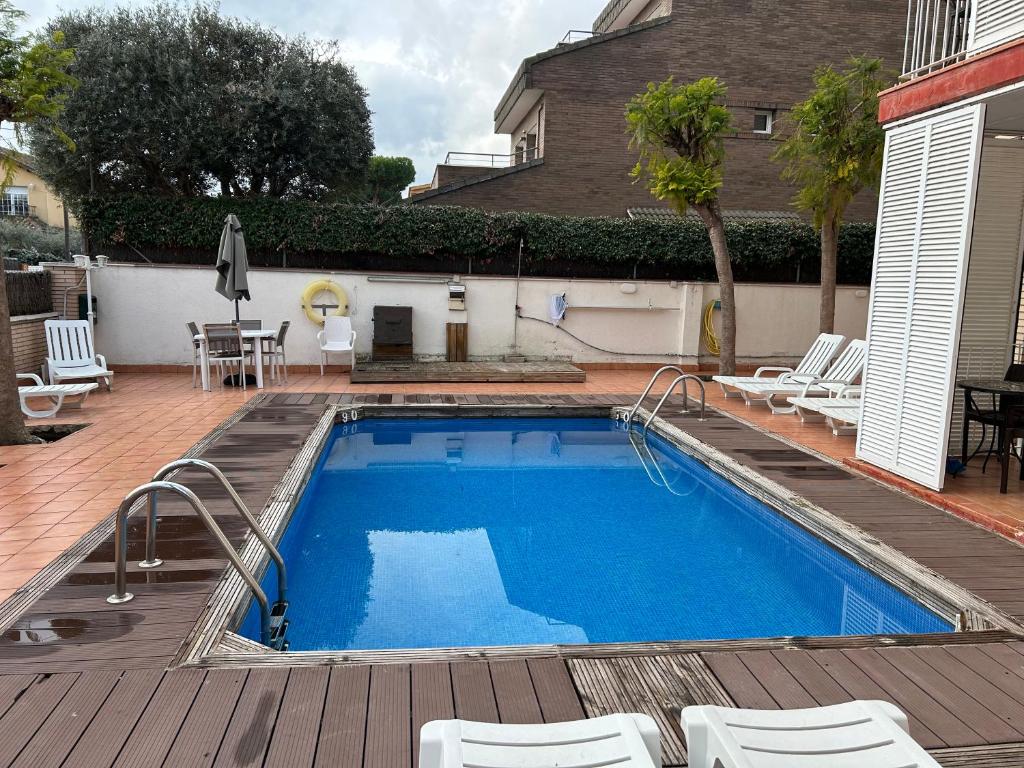 a pool on a deck with chairs and a table at Apartamentos ELMA1 in Castelldefels