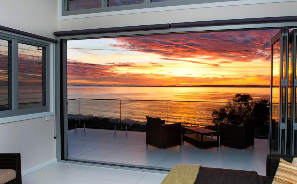 a view of a sunset from the balcony of a house at Allure at Hyams Beach - seconds to white sands in Hyams Beach