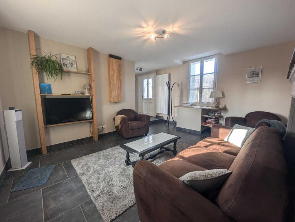 un salon avec un canapé et une télévision dans l'établissement Gite de la grand'cour, à Frampas