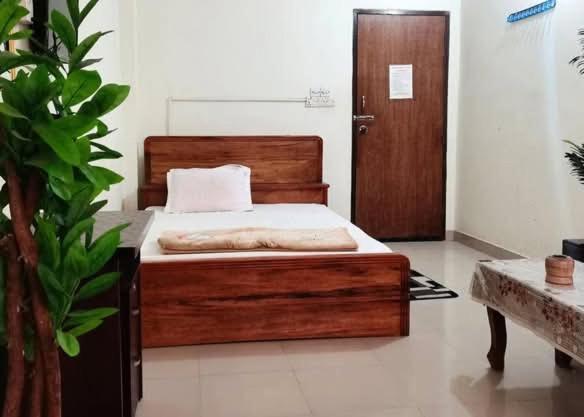 a bedroom with a wooden bed and a wooden door at রোজ ভ্যালি আবাসিক হোটেল in Dāsnaogaon