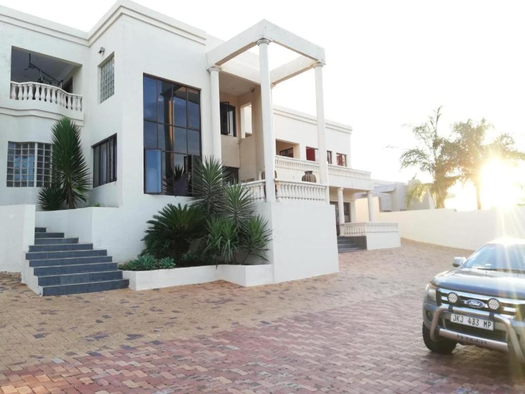 een wit huis met een auto ervoor geparkeerd bij Casadeross Guest House in Pretoria