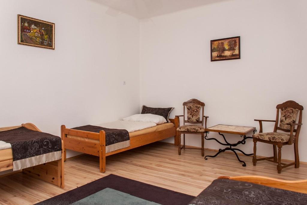 a room with two beds and a table and two chairs at Annabella Apartman in Tiszafüred