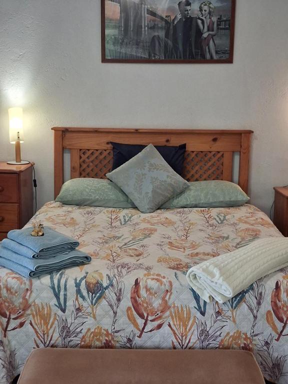 een slaapkamer met een bed met een bloemensprei en een schilderij bij Dombeya Ridge Guest Suite in Rustenburg