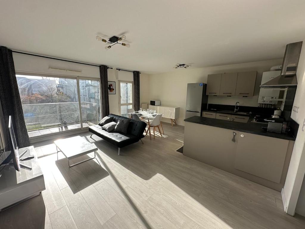 een keuken en woonkamer met een bank en een tafel bij T3 proche aéroport in Saint-Jacques-de-la-Lande