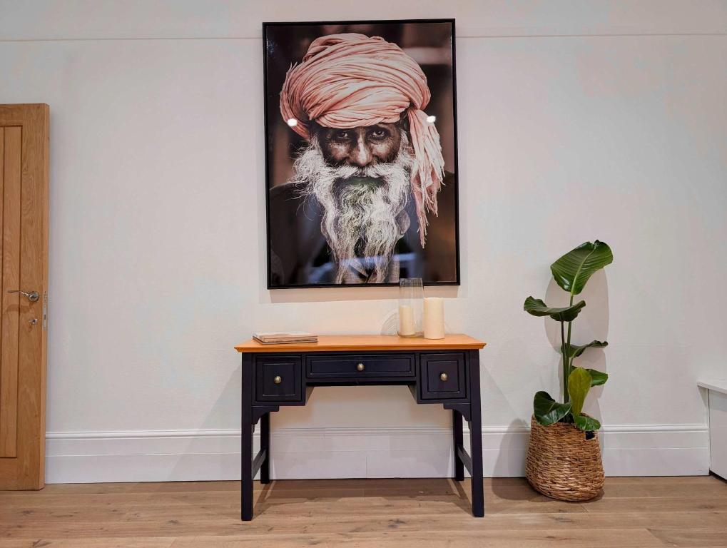 een tafel met een schilderij van een man met een baard bij Elegant 2-Bed Flat in Shenfield in Mountnessing