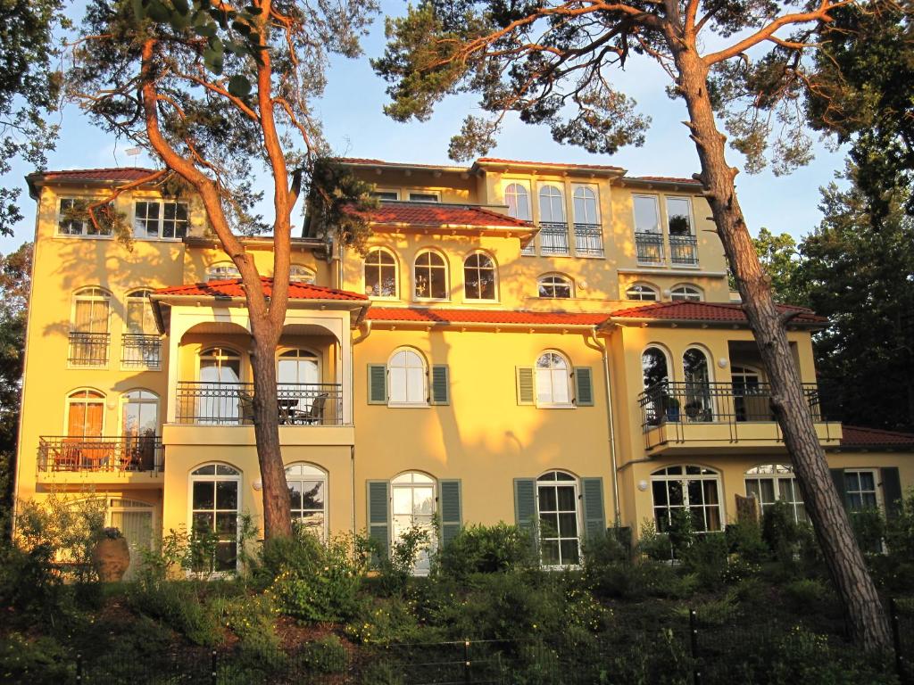 巴貝的住宿－Appartement Meeresrauschen，前面有树木的黄色建筑