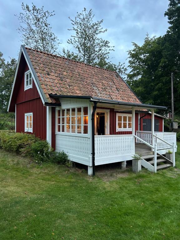 TrensumForrest cottage by the lake的一栋红色的房子，带一个大门廊和一个院子。