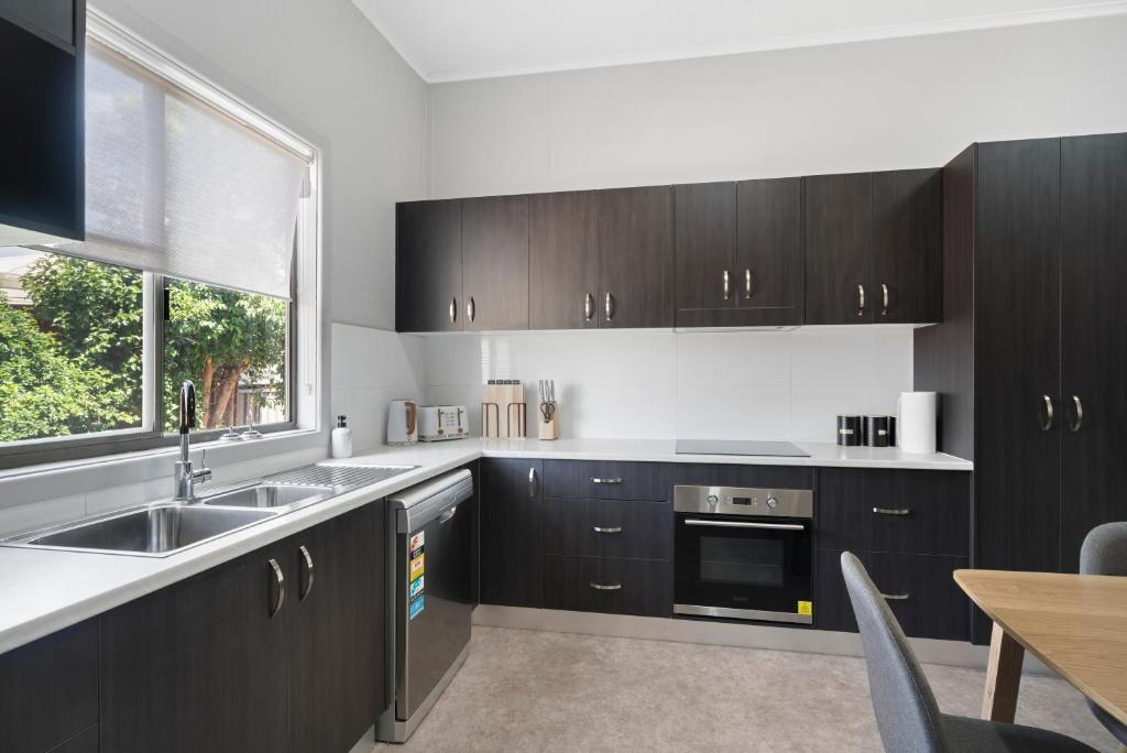 a kitchen with black cabinets and a sink and a window at Edwin Cottage Dubbo - close to the hospital in Dubbo