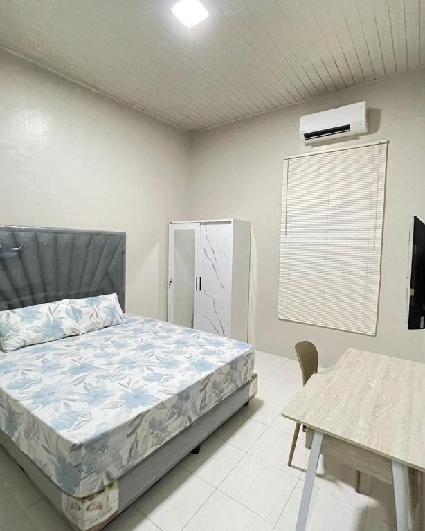 ein Schlafzimmer mit einem Bett, einem Tisch und einem Fernseher in der Unterkunft Utama Lueng Bata Hotel in Luengbata